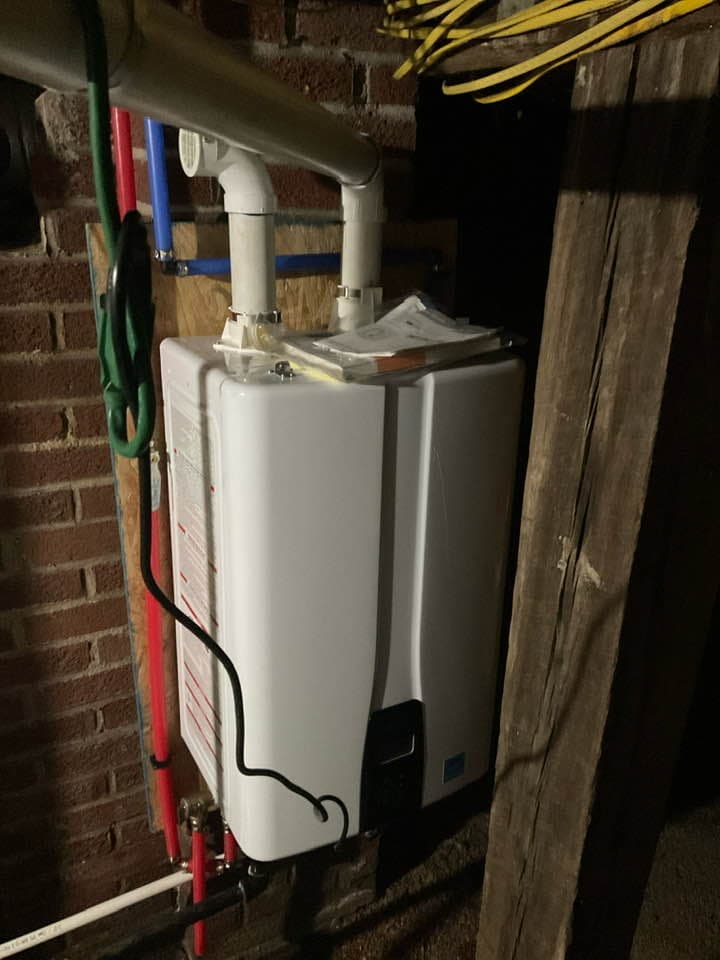 Tankless water heater installed against brick wall